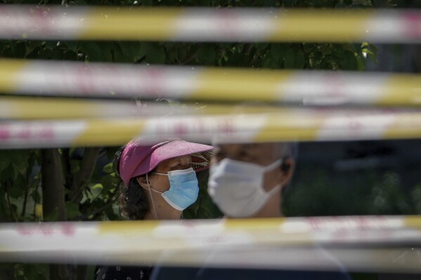 FILE - Residents wearing face masks line up behind barricaded tapes for COVID mass testing near a residential area on May 15, 2022, in Beijing. The World Health Organization says it’s made an official request to China for information about a potentially worrying spike in respiratory illnesses and clusters of pneumonia in children. (AP Photo/Andy Wong, File)