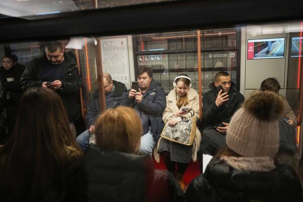 Passengers look at their smartphone while riding a subway car in Moscow, Russia, Tuesday, March 4, 2025. (AP Photo/Alexander Zemlianichenko)