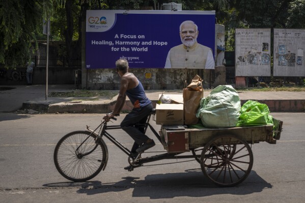 A man rides a cycle rickshaw past a billboard featuring Indian Prime Minister Narendra Modi ahead of this week's summit of the Group of 20 nations in New Delhi, India, Sept., 7, 2023. (AP Photo/Altaf Qadri, File)
