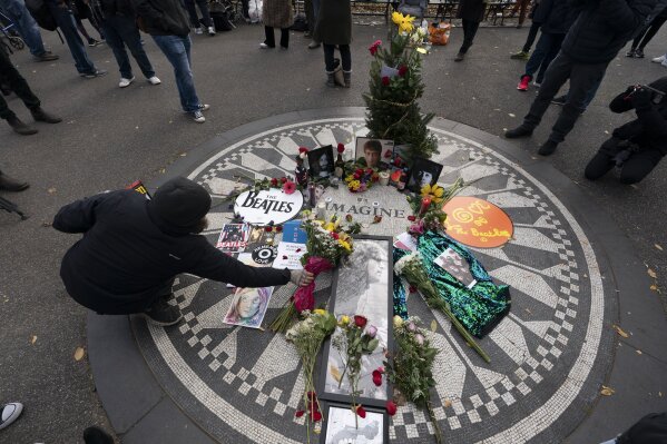 A man places flowers at Strawberry Fields in New York's Central Park to remember John Lennon, Tuesday, Dec. 8, 2020. The rock star and former Beatle was shot to death outside his New York City apartment building by a fan on Dec. 8, 1980. (AP Photo/Mark Lennihan)