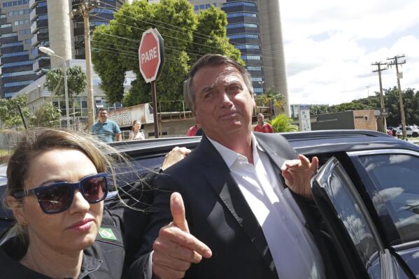 Former Brazilian President Jair Bolsonaro leaves after giving testimony over the Jan. 8 attacks on government buildings, at Federal Police headquarters in Brasilia, Brazil, Wednesday, April 26, 2023. Thousands of Bolsonaro supporters trashed the presidential palace, the Supreme Court and Congress one week into President Luiz Inácio Lula da Silva's third term in office. At left is a police agent. (AP Photo/Gustavo Morteno)
