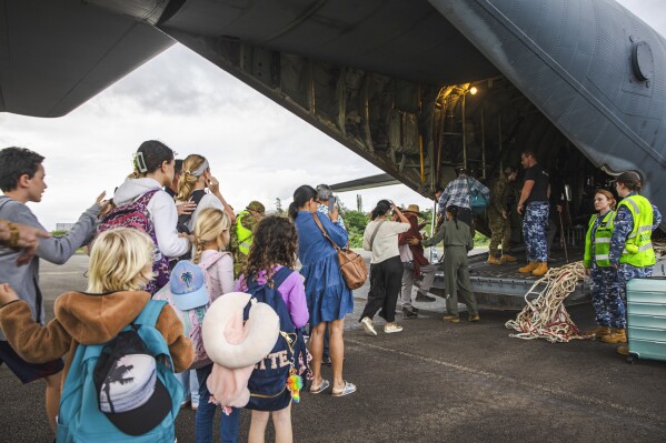 In this photo provided by the Australian Department of Defence, Australian and other tourists board an Australian Airforce Hercules as they prepare to depart from Magenta Airport in Noumea, New Caledonia, Tuesday, May 21, 2024. Australia and New Zealand have sent airplanes to New Caledonia to begin bringing home stranded citizens from the violence-wracked French South Pacific territory. (LAC Adam Abela/Royal Australian Airfare via AP)