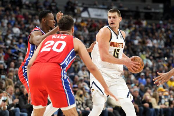 Denver Nuggets center Nikola Jokic, right, looks to drive to the rim as Philadelphia 76ers forward Georges Niang, front left, and center Charles Bassey defend in the first half of an NBA basketball game, Thursday, Nov. 18, 2021, in Denver. Philadelphia won 103-89. (AP Photo/David Zalubowski)
