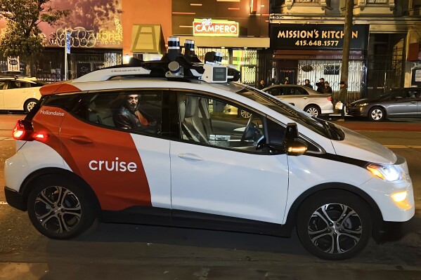 FILE - Associated Press reporter Michael Liedtke sits in the back of a Cruise driverless taxi that picked him up in San Francisco's Mission District, Feb. 15, 2023. General Motors is facing a U.S. Justice Department investigation into a gruesome collision involving a robotaxi operated by GM's Cruise subsidiary that critically injured a pedestrian and derailed its self-driving car ambitions, potentially worsening an already severe backlash. (AP Photo/Terry Chea, File)