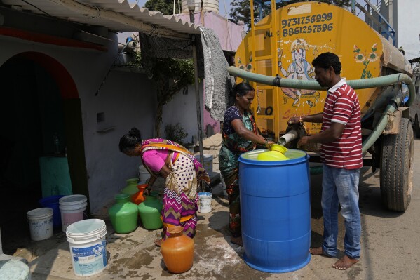 Residents of Ambedkar Nagar, a low-income settlement in the shadows of global software companies in Whitefield neighborhood, collect potable water from a private tanker in Bengaluru, India, Monday, March 11, 2024. Water levels are running desperately low, particularly in poorer regions, resulting in sky-high costs for water and a quickly dwindling supply. (AP Photo/Aijaz Rahi)