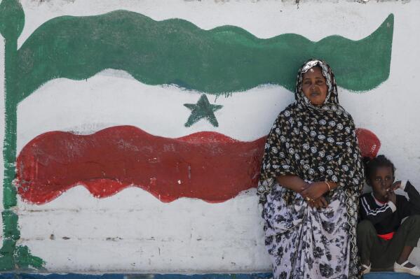 FILE - A woman and child relax next to a mural of Somaliland's flag, in Hargeisa, Somaliland, a semi-autonomous breakaway region of Somalia, on Feb. 9, 2022. The leader of Somaliland urged the international community on Monday, March 14 to recognize his territory's quest for independence, saying negotiations with Somalia had failed. (AP Photo/Brian Inganga, File)