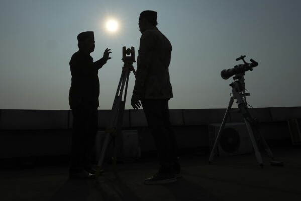 FILE - Officials are silhouetted as they use a telescope to scan the horizon for a crescent moon that will determine the beginning of the holy fasting month of Ramadan in Jakarta, Indonesia, Wednesday, March. 22, 2023. (AP Photo/Achmad Ibrahim, File)