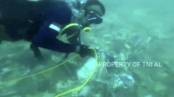In this image made from undated video released by Indonesian Navy (TNI AL), divers is seen recovering debris strewn on the sea floor in Java Sea where Sriwijaya Air passenger jet crashed, in Indonesia. The search for the black boxes of a crashed Sriwijaya Air jet intensified Monday to boost the investigation into what caused the plane carrying 62 people to nosedive at high velocity into the Java Sea. (Indonesian Navy via AP)