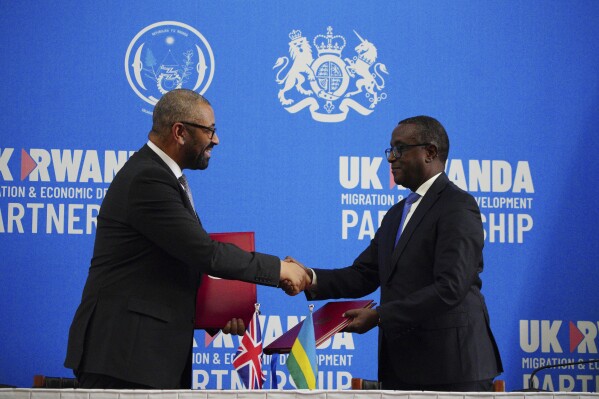 Britain's Home Secretary James Cleverly, left, and Rwandan Minister of Foreign Affairs Vincent Biruta shake hands after signing a new treaty in Kigali, Rwanda, Tuesday, Dec. 5, 2023. The treaty will address concerns by the Supreme Court, including assurances that Rwanda will not remove anybody transferred under the partnership to another country. (Ben Birchall/PA Wire via 鶹ýapp)