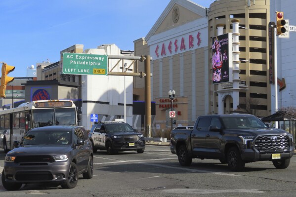 Traffic moves along Atlantic Avenue in Atlantic City, N.J. on Wednesday, Dec. 13, 2023, where a project was under way to reduce the main road through the gambling resort from four lanes to two. Federal and state funds that paid for the $24 million repaving and traffic light synchronization project also require a pedestrian safety component, in this case reducing the size of the roadway. (AP Photo/Wayne Parry)