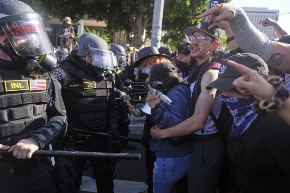 Protesters confront police on the 101 Freeway near the metropolitan detention center of downtown Los Angeles, Sunday, June 8, 2025, following last night's immigration raid protest. (AP Photo/Jae C. Hong)