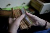 File - A worker counts money at a grocery store in Buenos Aires, Argentina, Nov. 21, 2023. In the past five years, Argentina's currency has lost about 90% of its value against the U.S. dollar. (AP Photo/Natacha Pisarenko, File)