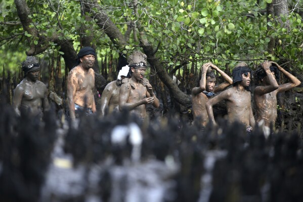 People of Kedonganan village leave a mangrove forest after their mud bath purification ritual as part of Balinese Hindu New Year celebrations in Bali, Tuesday, March 12, 2024. (AP Photo/Firdia Lisnawati)