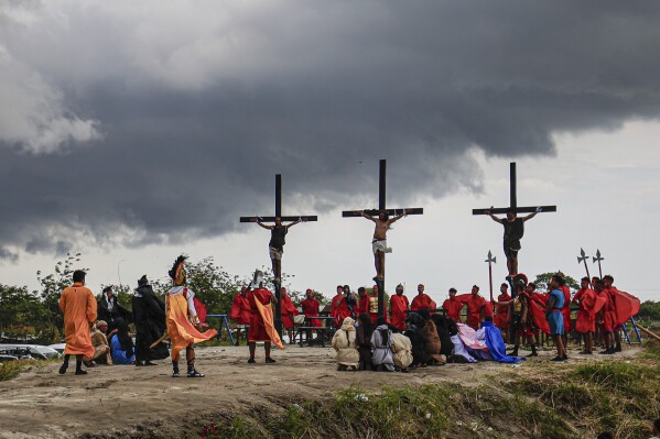 Ruben Enaje, uprostřed, zůstává na kříži obklopen dvěma dalšími věřícími během rekonstrukce utrpení Ježíše Krista v rámci rituálů Velkého pátku v San Pedro Cutud, severně od Manily na Filipínách, pátek 29. března 2024. (AP Photo /Gerard) V.  mršina)