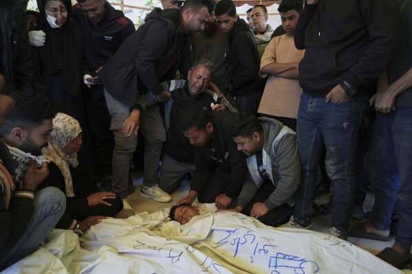 Mourners grieve over the body of Palestinian child Mohammad Abu Nada, killed in an Israeli army airstrike, during his funeral in Khan Younis, southern Gaza Strip, on Saturday, April 19, 2025. (AP Photo/Abdel Kareem Hana)
