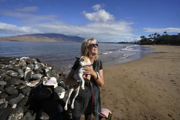 Anne Landon camina por la playa con su perro, LaVida, el martes 15 de agosto de 2023 en Kihei, Hawái.  Landon ha buscado ayuda para sobrellevar la ansiedad que siguió al devastador incendio forestal en Maui.  (Foto AP/Rick Bowmer)