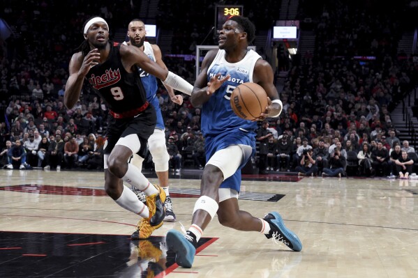 Minnesota Timberwolves guard Anthony Edwards, right, drives to the basket against Portland Trail Blazers forward Jerami Grant during the first half of an NBA basketball game in Portland, Ore., Thursday Feb. 15, 2024. (AP Photo/Steve Dykes)
