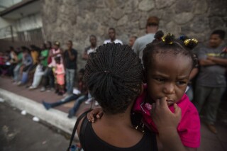 FILE - A Haitian woman carries her daughter as she waits outside the Mexican Commission for Migrant Assistance office, to get the documents needed that allow them to stay in Mexico, in Tapachula, early Thursday, June 20, 2019. Migrants, mostly from Haiti, have burst Monday, Sept. 18, 2023, into an asylum office in Tapachula, to demand papers. (AP Photo/Oliver de Ros, File)