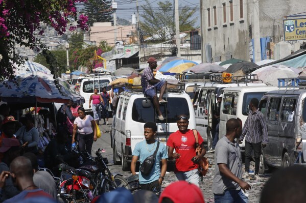 Pedestrians and commuters fill a street in Port-au-Prince, Haiti, Tuesday, March 12, 2024. Haitian Prime Minister Ariel Henry announced Tuesday that he would resign once a transitional presidential council is created, bowing to international pressure to make way for new leadership in the country overwhelmed by violent gangs. (AP Photo/Odelyn Joseph)