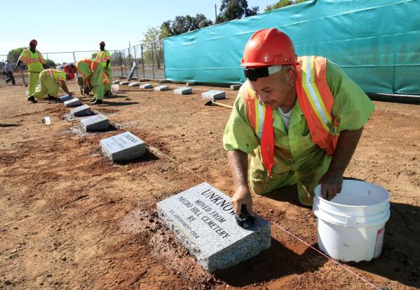 FILE - Steven Abujen, a California prison inmate with the Prison Industry Authority, cleans one of the newly installed headstones at the Mormon Island Relocation Cemetery, near Folsom, Calif., on Oct. 18, 2011. Lawmakers in Nevada and California are advancing legislation to remove involuntary servitude from their state constitutions, a move that follows four states that purged forced labor from the books in ballot measures last fall. (AP Photo/Rich Pedroncelli, File)