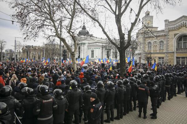 Riot police officers stand in line in front of protesters during a protest initiated by the Movement for the People and members of Moldova's Russia-friendly Shor Party, against the pro-Western government and low living standards, in Chisinau, Moldova, Tuesday, Feb. 28, 2023. Thousands of protesters returned to Moldova's capital Tuesday to demand that the country'snew pro-Western governmentfully subsidize citizens' winter energy bills amid skyrocketing inflation. (AP Photo/Aurel Obreja)