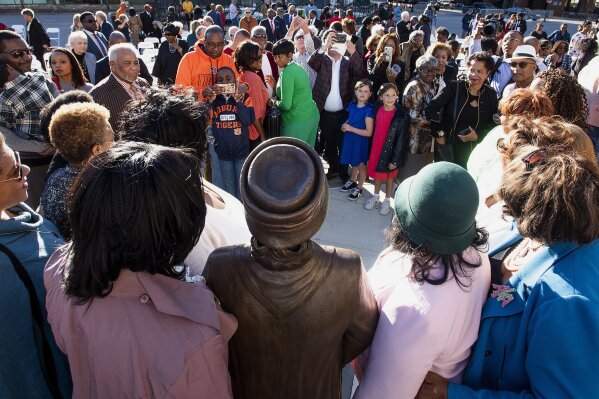 Attendees gather to have their photos made with the Rosa parks statue after its unveiling in downtown Montgomery, Ala., Sunday, Dec. 1, 2019, the anniversary of her arrest for not giving up her seat on a city bus. (Mickey Welsh/Montgomery Advertiser via AP)