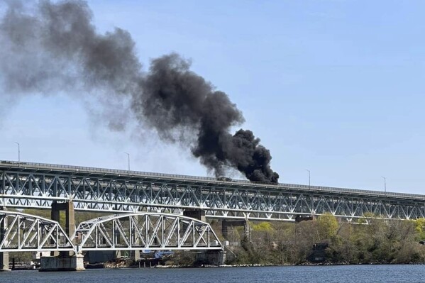 FILE - In this photo provided by the Connecticut State Police, plumes of smoke rise from a fire resulting from crash involving a fuel truck and a car on the Gold Star Memorial Bridge in Groton, Conn., Friday, April 21, 2023. A man accused of causing the fiery crash that shut down a major Connecticut highway bridge and killed a truck driver has been charged with negligent homicide, police said Thursday, April 25, 2024. (Connecticut State Police via AP, File)
