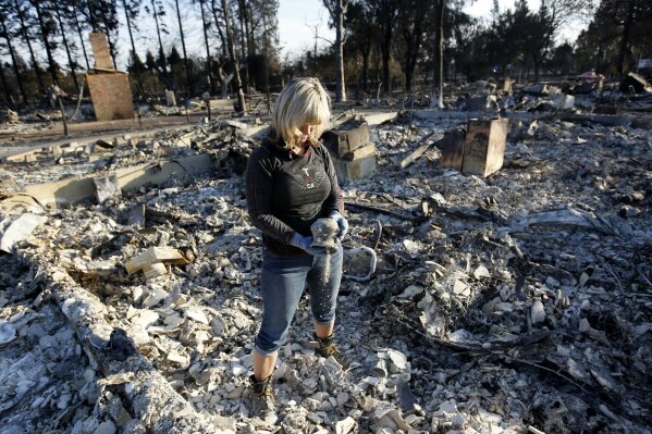 
              Debbie Wolfe dumps ashes from a pot she found in the burned ruins of her home Tuesday, Oct. 17, 2017, in Santa Rosa, Calif. A massive deadly wildfire swept through the area last week destroying thousands of housing and business. (AP Photo/Rich Pedroncelli)
            