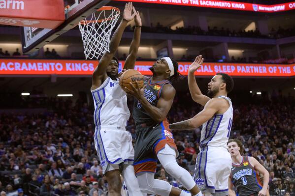 Sacramento Kings forward Chimezie Metu, left, and Oklahoma City Thunder guard Luguentz Dort collide under the basket during the first half of an NBA basketball game in Sacramento, Calif., Friday, Jan. 20, 2022. (AP Photo/Randall Benton)
