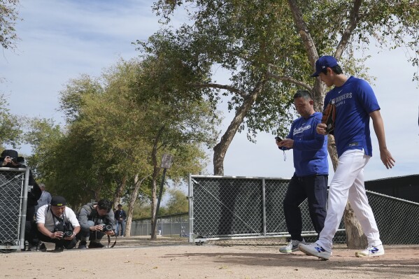 Los Angeles Dodgers' Shohei Ohtani, right, of Japan, walks back to the clubhouse at the Dodgers baseball spring training facility after working out Tuesday, Feb. 11, 2025, in Phoenix. (AP Photo/Ross D. Franklin)
