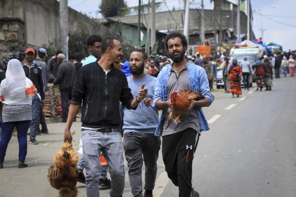 Men carry chickens home after buying them at Sholla Market, the day before the Ethiopian New Year, in Addis Ababa, Ethiopia Saturday, Sept. 10, 2022. Once home to one of Africa's fastest growing economies, Ethiopia is struggling as the war in its Tigray region has reignited and Ethiopians are experiencing the highest inflation in a decade, foreign exchange restrictions and mounting debt amid reports of massive government spending on the war effort. (AP Photo)