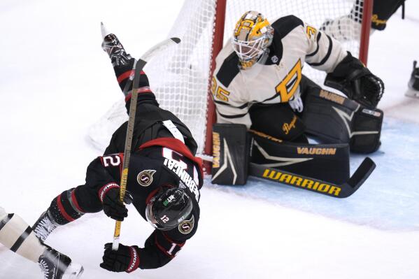 Ottawa Senators' Alex DeBrincat (12) collides with Pittsburgh Penguins' Bryan Rust, partially in frame at left, in front of Penguins goaltender Tristan Jarry (35) during the first period of an NHL hockey game in Pittsburgh, Friday, Jan. 20, 2023. (AP Photo/Gene J. Puskar)