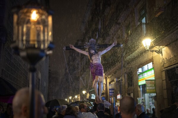 Worshippers carry an image of the Holy Christ of the Blood while it rains, during a procession through the streets of downtown Barcelona, Spain, Saturday, March 9, 2024. Preceded by nine days of prayers and emulating a documented historical tradition dating back five hundred years, worshippers requested rain as Catalonia last month declared drought emergency for the area of around 6 million people including the city of Barcelona. (AP Photo/Emilio Morenatti)