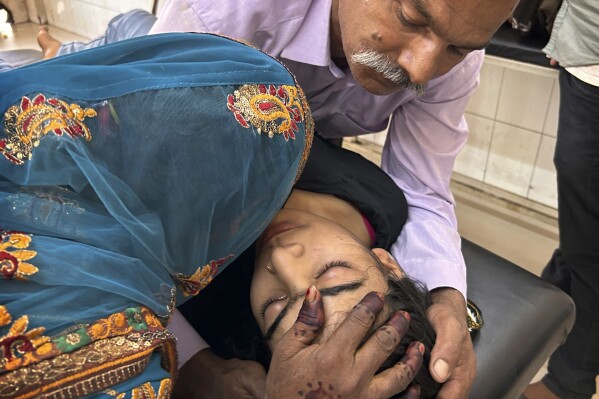 A couple try to pacify their daughter suffering from heat related ailment as she is brought to the government district hospital in Ballia, Uttar Pradesh state, India, Monday, June 19, 2023. Several people have died in two of India's most populous states in recent days amid a searing heat wave, as hospitals find themselves overwhelmed with patients. More than hundred people in the Uttar Pradesh and dozens in neighboring Bihar have died due to heat-related illness. (AP Photo/Rajesh Kumar Singh)