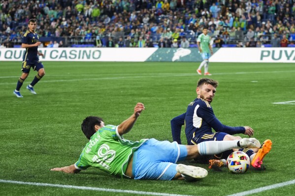 Vancouver Whitecaps defender Tristan Blackmon blocks a shot from Seattle Sounders midfielder Obed Vargas (18) during the first half of an MLS soccer match Saturday, May 18, 2024, in Seattle. (AP Photo/Lindsey Wasson)