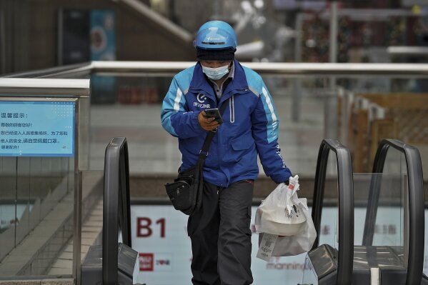 A food delivery worker wearing a face mask to help curb the spread of the coronavirus prepares to deliver foods for his customers at a shopping mall in Beijing on Thursday, Jan. 14, 2021. The e-commerce workers and delivery people who kept China fed during the pandemic, making their billionaire bosses even richer, are so unhappy with their pay and treatment that one just set himself on fire in protest. (AP Photo/Andy Wong)