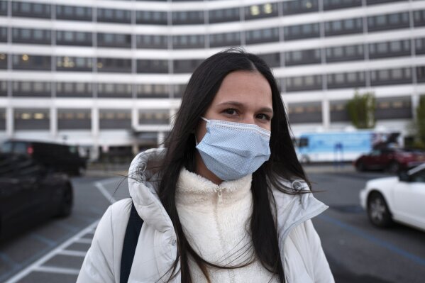 Nurse Heather Espinal stands in front of the James J. Peters Department of Veterans Affairs Medical Center where she works, Wednesday, April 22, 2020, in the Bronx borough of New York. The nation's largest health care system was unprepared for the coronavirus outbreak, with nurses at Veterans Affairs facilities around the country complaining that a shortage of equipment and staffing left them vulnerable and, in some cases, caused them to contract the virus. (AP Photo/Mark Lennihan)