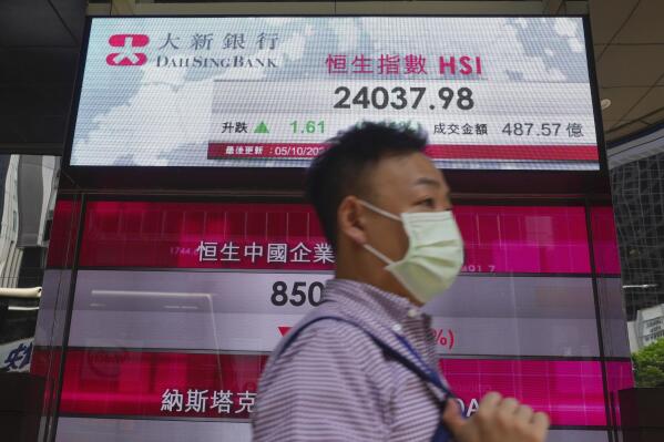 A man walks past a bank's electronic board showing the Hong Kong share index at Hong Kong Stock Exchange in Hong Kong Tuesday, Oct. 5, 2021. Shares have fallen in Asia after a broad slide on Wall Street led by technology companies. (AP Photo/Vincent Yu)