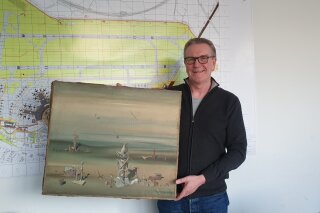In this photo released by the police department in Duesseldorf on Thursday Dec. 10, 2020, showing Chief Detective Michael Dietz holding a painting from French artist Yves Tanguy. A businessman, whose identity was not given, boarded a flight from Duesseldorf to Tel Aviv on Nov. 27, but forgot the painting by French surrealist Yves Tanguy, which was wrapped in cardboard, on the check-in counter. By the time he landed in Israel and contacted Duesseldorf police, the 280,000 Euro, (dollar 340,000), oeuvre had disappeared but was later found at a nearby paper dumpster, Duesseldorf police said. (Polizei Duesseldorf via AP)
