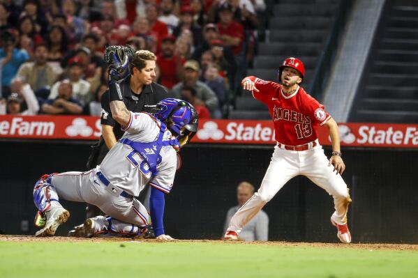 Los Angeles Angels' Livan Soto, right, reacts after he scored against Texas Rangers catcher Jonah Heim, left, during the seventh inning of a baseball game in Anaheim, Calif., Saturday, Oct. 1, 2022. (AP Photo/Ringo H.W. Chiu)