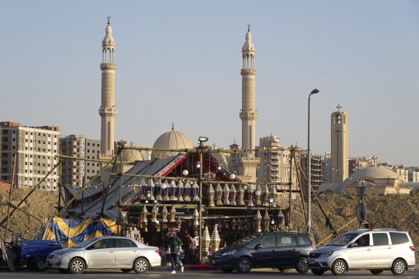 People buy traditional lanterns in front of a shop ahead of the upcoming Muslim fasting month of Ramadan, in Cairo, Egypt, Sunday, March 10, 2024. Muslims around the world are preparing to celebrate Ramadan, the holy month sacred of the Islamic calendar, abstaining from eating, drinking, smoking and having sex from dawn to dusk.  (AP Photo/Amr Nabil)