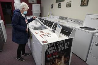 Alanna Kelly, of Norwood, Mass., examines clothes washers and dryers on display at Sam's Appliances TV & Furniture, Thursday, March 25, 2021, in Norwood. U.S. consumer confidence surged in March to the highest reading in a year, helped by increased vaccinations and more government economic support. The Conference Board said Tuesday, March 30, its consumer confidence index rose to 109.7 in March, the best showing since it stood at 118.8 in March of last year as the pandemic was beginning to hit the United States. (AP Photo/Steven Senne)