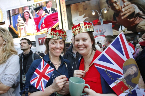 FILE - Molly Davis, left, and Amanda D'Aquila join a large crowd in New York's Times Square to watch the royal wedding, April 29, 2011. The pomp, the glamour, the conflicts, the characters — when it comes to the United Kingdom’s royal family, the Americans can’t seem to get enough. (AP Photo/Mark Lennihan, File)