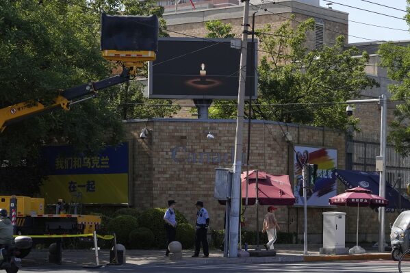 A boom lift partially blocks the view of a screen depicting a lit candle at the Canadian Embassy on the anniversary of China's bloody 1989 crackdown on pro-democracy protests in Beijing, Wednesday, June 4, 2025. (AP Photo/Ng Han Guan)
