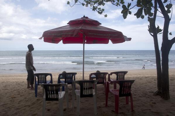 A beach vendor sets chairs as he waits for customers in Kuta beach in Bali, Indonesia, Thursday, Oct. 14, 2021. The Indonesian resort island of Bali welcomed international travelers to its shops and white-sand beaches for the first time in more than a year Thursday - if they're vaccinated, test negative, hail from certain countries, quarantine and heed restrictions in public. (AP Photo/Firdia Lisnawati)