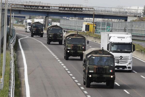 FILE - In this file photo, military trucks moving coffins of deceased people line up on the highway next to Ponte Oglio, near Bergamo, one of the areas worst hit by the coronavirus infection, on their way from Bergamo cemetery to a crematory in some other location as the local crematory exceeded its maximum capacity. Italy on Friday marked the second anniversary of a tragic milestone of the coronavirus pandemic, the day when a convoy of army trucks had to transport the dead out of hard-hit Bergamo because the city’s cemeteries and crematoria were full. (AP Photo/Luca Bruno, File)