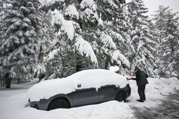 FILE - A man shovels snow off his car in the Cleveland National Forest, on Feb. 7, 2024, in eastern San Diego county, Calif. California's current rainy season got off to a slow start but has rebounded with recent storms that have covered mountains in snow and unleashed downpours, flooding and mudslides. The water content of the vital Sierra Nevada snowpack has topped 80% of normal to date while downtown Los Angeles has already received more than an entire year's average annual rainfall. (AP Photo/Denis Poroy, File)