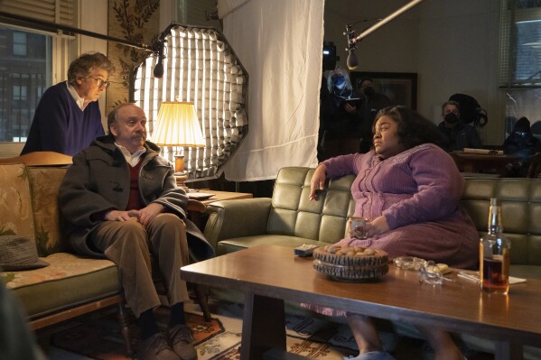 This image released by Focus Features shows director Alexander Payne, background left, with actors Paul Giamatti and Da'Vine Joy Randolph, right, on the set of their film 