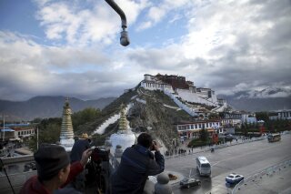 
              FILE - In this Sept. 19, 2015 file photo, tourists take photos of the Potala Palace beneath a security camera in Lhasa, capital of the Tibet Autonomous Region of China. A Tibetan man set himself on fire in a traditionally Tibetan area of China's Sichuan province and died in a protest Sunday, Nov. 4, 2018, a rights monitoring group reported. (AP Photo/Aritz Parra, File)
            