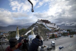 FILE - In this Sept. 19, 2015 file photo, tourists take photos of the Potala Palace beneath a security camera in Lhasa, capital of the Tibet Autonomous Region of China. A Tibetan man set himself on fire in a traditionally Tibetan area of China's Sichuan province and died in a protest Sunday, Nov. 4, 2018, a rights monitoring group reported. (AP Photo/Aritz Parra, File)